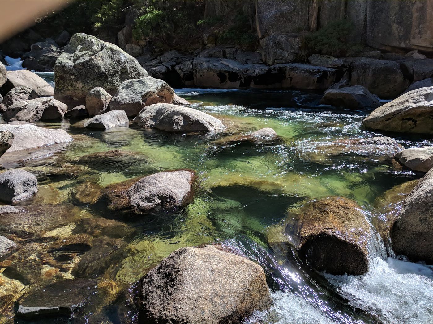 Raw phone photo of a rocky mountain river, flat and washed out